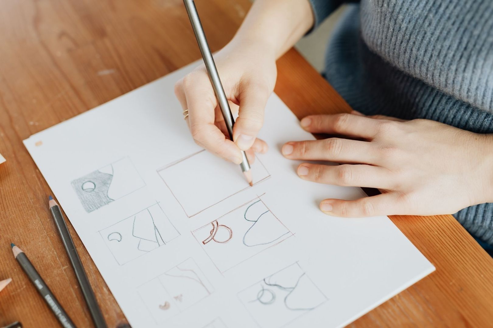 Main dessinant au crayon des esquisses de formes et de logos